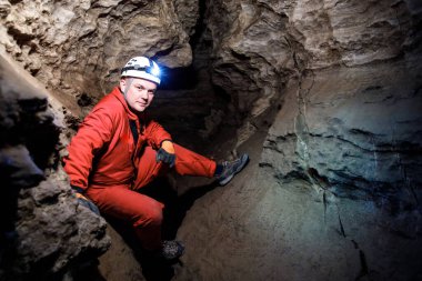 Adam yer altında aydınlık far ile karanlık mağarayı keşfediyor. Gizemli derin karanlık, kâşif gizemli kasvetli tüneli keşfediyor ve içerideki kaya duvarına bakıyor..