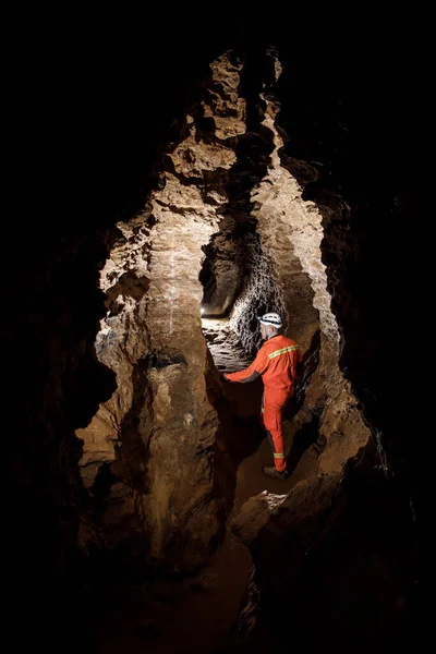 Uomo passeggiando ed esplorando grotta buia con luce fari sotterranei. Misterioso profondo buio, esploratore scoprire mistero tunnel lunatico guardando sulla parete rocciosa all'interno . — Foto Stock