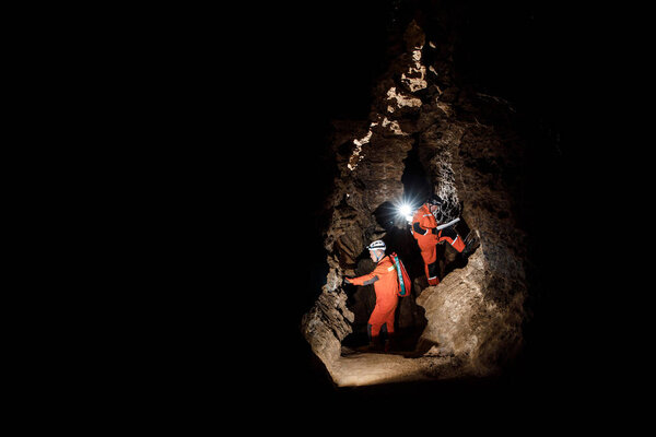Two men, strong physique, explore the cave. Men dressed in special clothes to pass through the cave and stopped, looking at the map