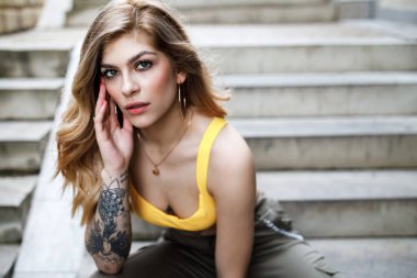 Merdivenlerde oturan bir kadının sokak modası yaz portresi