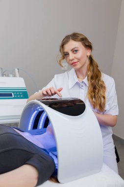 Güzellik uzmanı, modern bir klinik ortamında gelişmiş cilt bakımı için profesyonel bir güzellik makinesi kullanıyor.