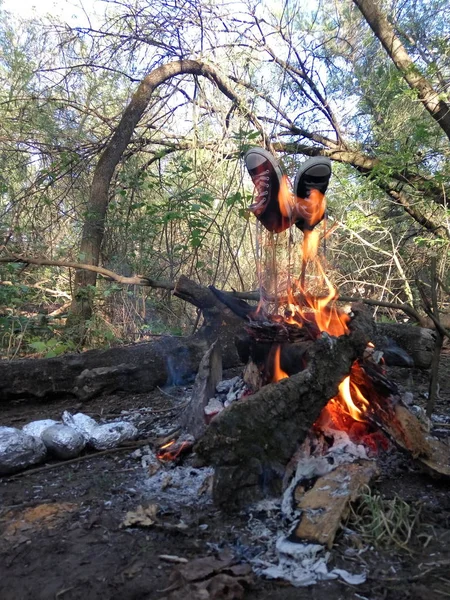 sneakers on a stick near fire in the open air