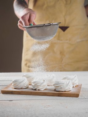 Kadın el tarafından pudra şekeri ile beyaz ev yapımı zephyr.