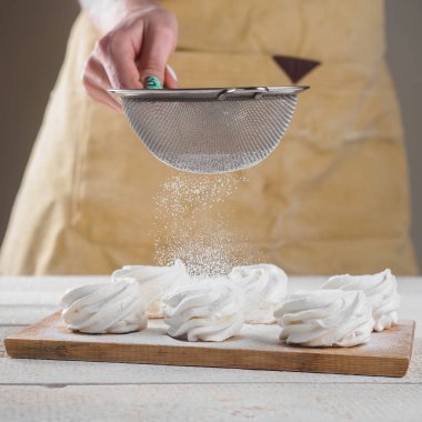 Kadın el tarafından pudra şekeri ile beyaz ev yapımı zephyr.