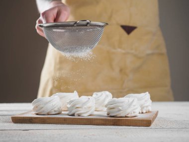 Kadın el tarafından pudra şekeri ile beyaz ev yapımı zephyr.