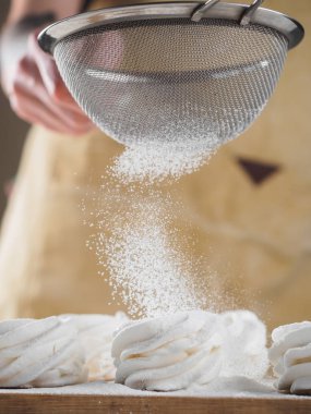 Kadın el tarafından pudra şekeri ile beyaz ev yapımı zephyr.