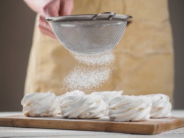 Kadın el tarafından pudra şekeri ile beyaz ev yapımı zephyr.