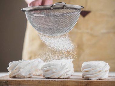 Kadın el tarafından pudra şekeri ile beyaz ev yapımı zephyr.