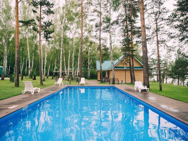 Бассейн и шезлонги в сосновой роще
.