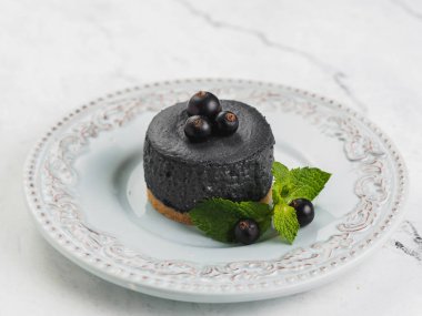 Frenk üzümü berry ile yuvarlak siyah mini cheesecake.