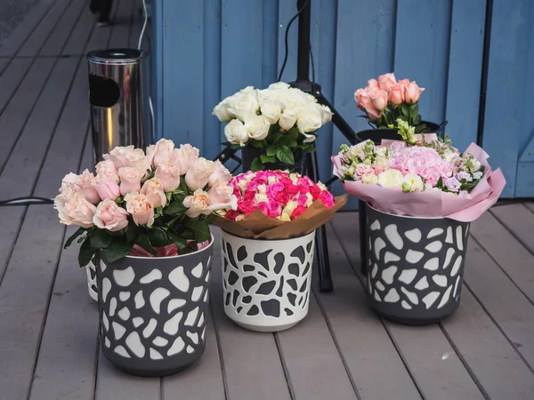 Buckets with flowers roses on wooden floor.