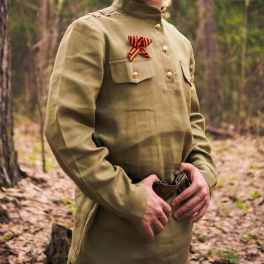 Man in soviet war uniform in forest. Victory day reenactment clipart