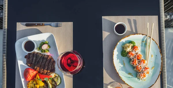 Steak sapi dengan sayuran panggang dan roti gulung sushi di atas meja — Stok Foto