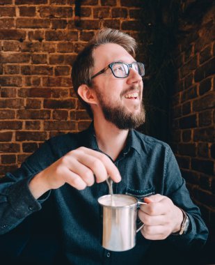 Diş mineli kahve fincanı olan mutlu sakallı adam. Tuğla duvar.