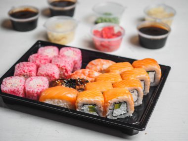 Beyaz arka planda plastik kutular içinde suşi ruloları..