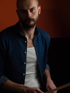 Çocuk kot gömlek ve koyu arka plan ile davul çalmaya