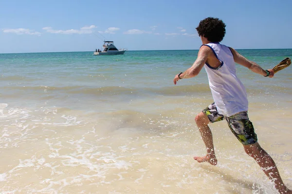 Een jonge kerel loopt in de zee. — Stockfoto