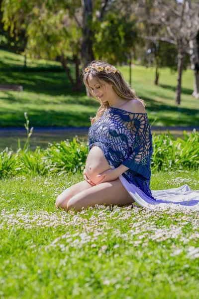Charming pregnant woman sitting on green meadow — Stock Photo, Image