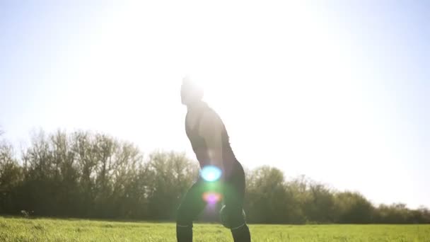Атлетический мужчина поднимает осанку в черный цвет спортивной wear.Outdoors. Зеленая трава. Видеозапись снизу — стоковое видео