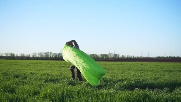 Un hombre está tratando de atrapar el viento para hacer cama inflable. Color verde. Hermoso prado — Vídeo de stock