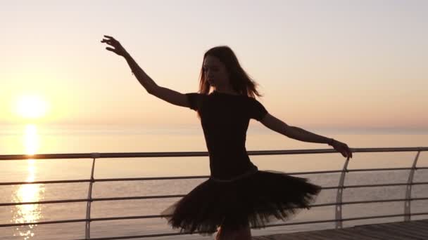Una bailarina practicando un baile de ballet cerca del mar. Preparando y haciendo un salto. Maravillosa luz del sol en el backstage. Movimiento lento — Vídeo de stock