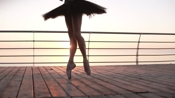 Detailní záběr elegantní baletní tanečníci noh, šlápnutí na dřevěné nábřeží na tip prsty v pointes. Černá baletní sukně. Krásná scéna s ranní slunce, které vychází v perspektivě — Stock video