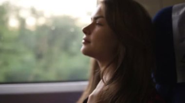 Dalgın kadın rahatlatıcı ve tren pencereden dışarı bakıyor. Yan görünümü. Seyahat, ulaşım kavramı
