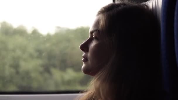 Vista lateral de una relajada, de pelo largo hermosa chica montando en el tren de velocidad. Perfil. Sentada cerca de la ventana. Mujer reflexiva y tranquila — Vídeos de Stock