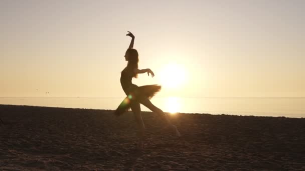 在海边的芭蕾舞短裙和尖角鞋芭蕾舞演员的剪影。练习芭蕾动作和姿势。清晨阳光围绕着优雅的芭蕾舞演员身体。慢动作 — 图库视频影像