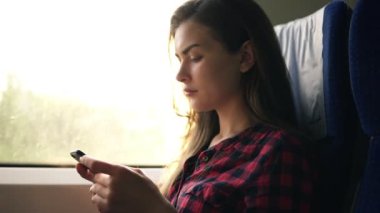 Çekici erkek ekose gömlekli trenle gidiyor, pencerenin yanında oturan ve ciddi görünümlü cep telefonu. Yan görünümü. Taşıma, hareket