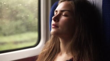 Tren ile seyahat eden muhteşem bir genç kadının görüntüleri nişan al. Şekerleme var. Gözlerin kapalı. Pencerenin oturuyor. Uzun saçlı esmer