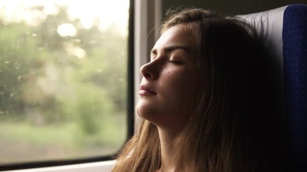 Una hembra franca que viaja en tren y se duerme cuando el paisaje pasa. Hermosa joven morena. Cara de cerca — Vídeos de Stock