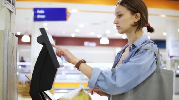 Ein Mädchen Wiegt Supermarkt Bananen Auf Einer Elektronischen Waage Und — Stockvideo