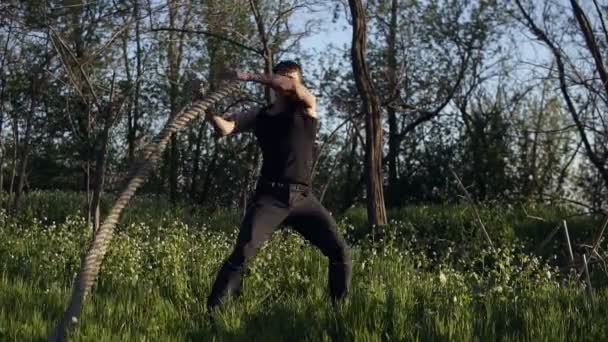 Utbildning på crossfit på öppen mark, park. Sportsmanen kastar repen från sida till sida, med kraft. Framifrån — Stockvideo