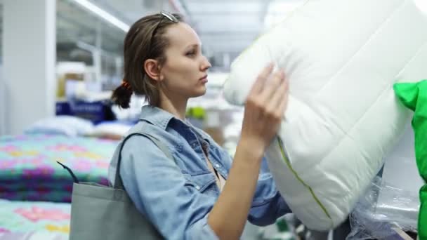 Mujer linda, positiva caucásica en la tienda. Concepto de compras. Toma una almohada suave del estante y pon su cabeza sobre ella. Tomar una siesta, divertirse, sonreír — Vídeo de stock