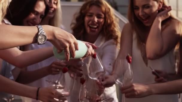 Hermosas señoritas celebran. Fiesta de gallinas. Sacudiendo una extraña botella de champán y dejándola rociar. La chica vierte una bebida en vasos. Afuera. Glamorosa fiesta. Movimiento lento — Vídeos de Stock