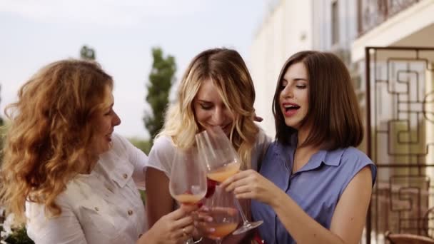 Концепция девичника. Три красивые женщины пьют коктейли вместе на террасе. Женщины болтают и смеются. Медленное движение — стоковое видео