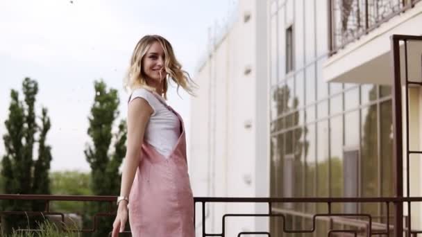 Young, stunning blonde girl is sprinkle the confetti out from the balcony. Calling out for her girlfriends. Everybody spread out the silver confetti. Beautiful stylish women. Hen party concept — Stock Video