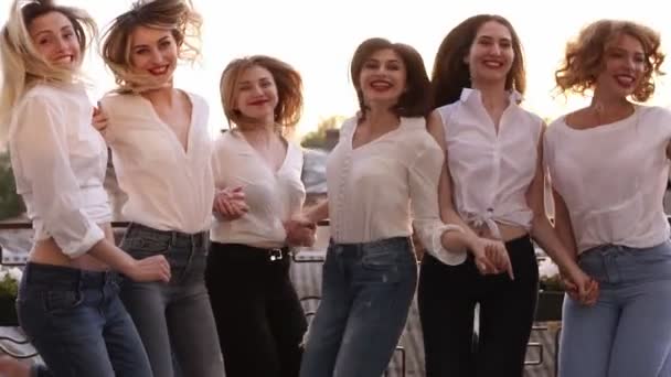 Happy smiling outside on a balcony terrace. Building, city landscape background jumping together in slow motion. Having fun together, fashionable female in same clothes laughing. Enjoyment life — Stock Video