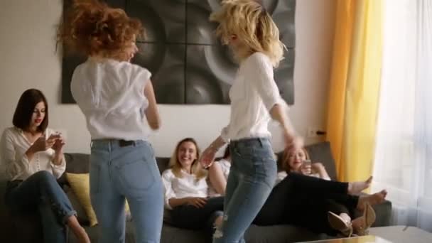 Fiesta de gallinas. Un grupo de seis chicas atractivas se divierten. Dos chicas bailan locas. Ropa casual idéntica. Emocionalmente conmovido. En interiores. Movimiento lento — Vídeo de stock