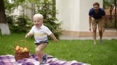 Sevimli, küçük oğlu ile gülümseyen baba. Annesine çalışan çocuk kimliği. Neşeli. Genç öpüşme ve sarılma benimsemesi sarışın çocuk, anne. O zaman babalar kollarını gider. Piknik kavramı. Ağır çekim