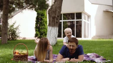Mutlu neşeli genç Aile Baba, anne ve açık havada eğleniyor, araya yaz park, kırsal oynayan küçük oğlu. Anne, baba ve oğul babalar üzerinde geri junping ve gülüyor. Beyaz Saray