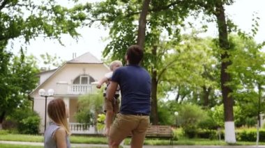 Güzel kırsal cottages arka ile. Yeşil park. Küçük sarışın çocuk babası için çalışıyor. Yakaladı onu ve hava atar. Aile pikniği