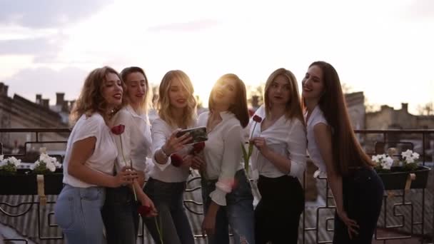Känslomässiga brudtärna och attraktiva flickvänner talar selfie med mobiltelefon och leende. Vita tjejer i vita skjortor poserar och hålla blommor i händerna. Utomhus. Framifrån — Stockvideo