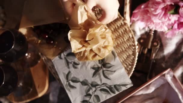 Close up of female hands open a small paper bag with cheese cut into cubes. Wine glasses. Picnic concept. Footage from the top — Stock Video