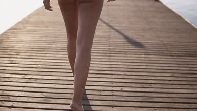 Arka güzel tabaklanmış birkadın iskelede yürüyüş şık gümüş mayo görüntüleri izleme. Kendine güvenen, neşeli genç bayan. Yaz günü