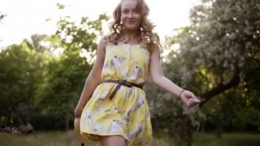 Mutlu, kendine güvenen genç kadın tarafından yeşil yazlık elbise parkta elinde hasır şapka ile yürüme. Önden görünüm. Düşük açılı görüntüleri