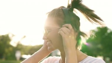 Bir kulaklık ile müzik ritmiyle dans sarı saçlar kız kapatın. Önden Görünümü delilik içinde başını sallayarak mutlu bir kadın. Açık havada. Ağır çekim