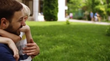 Mutlu, gülümseyen aile. Anne, Baba, küçük oğlu birbirlerine sarılıyorlar. Küçük bir çocuk ve onun kocası öpüşme anne. Mutlu çift. Yeşil park. Ağır çekim