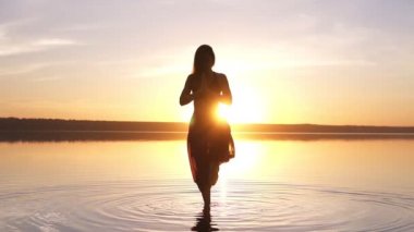 Sunset Beach, kadının yoga asana Utthita Hasta Padagushthasana suyun içinde kalan yapması güzel görüntüleri. Ağır çekim